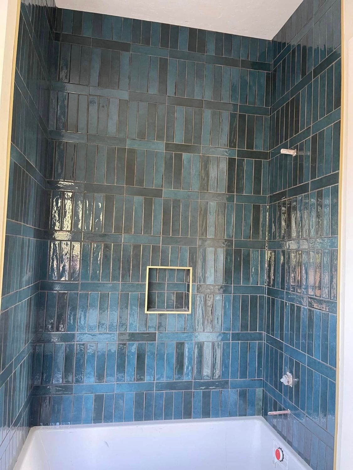 A bathroom with blue tiles and a bathtub.
