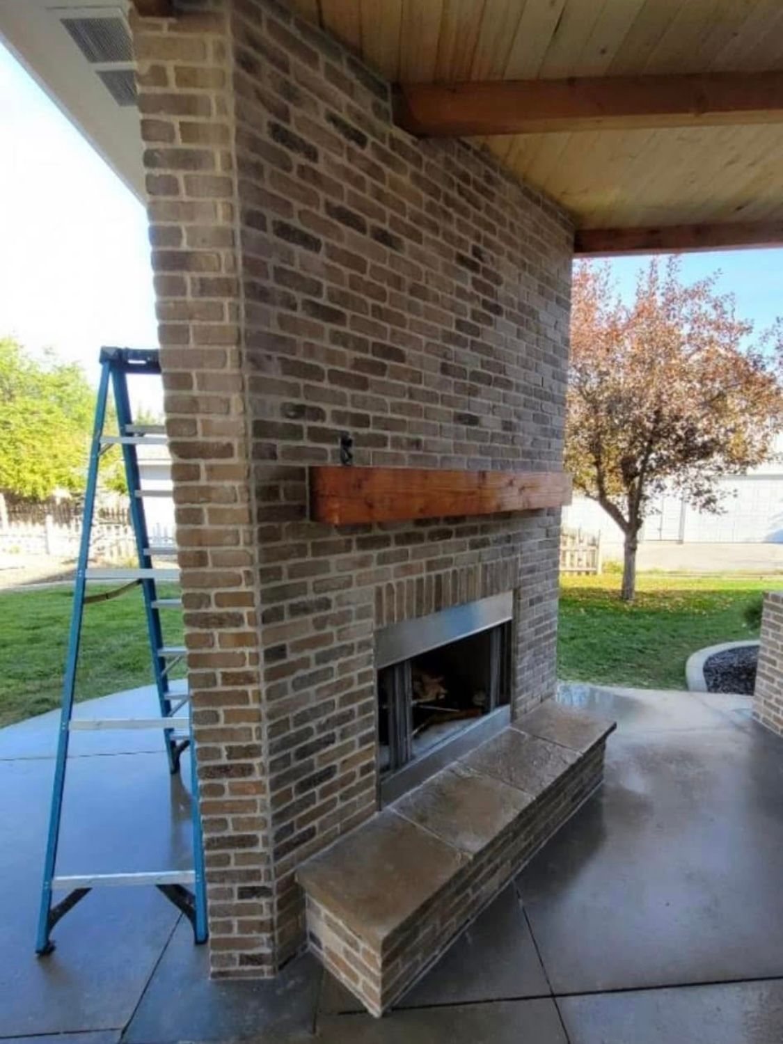 A ladder is sitting next to a brick fireplace.