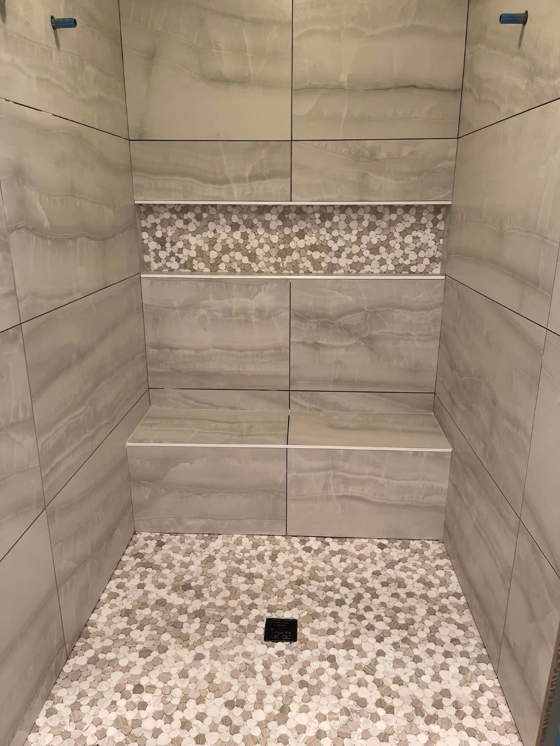 A shower stall with a bench and a tiled floor.