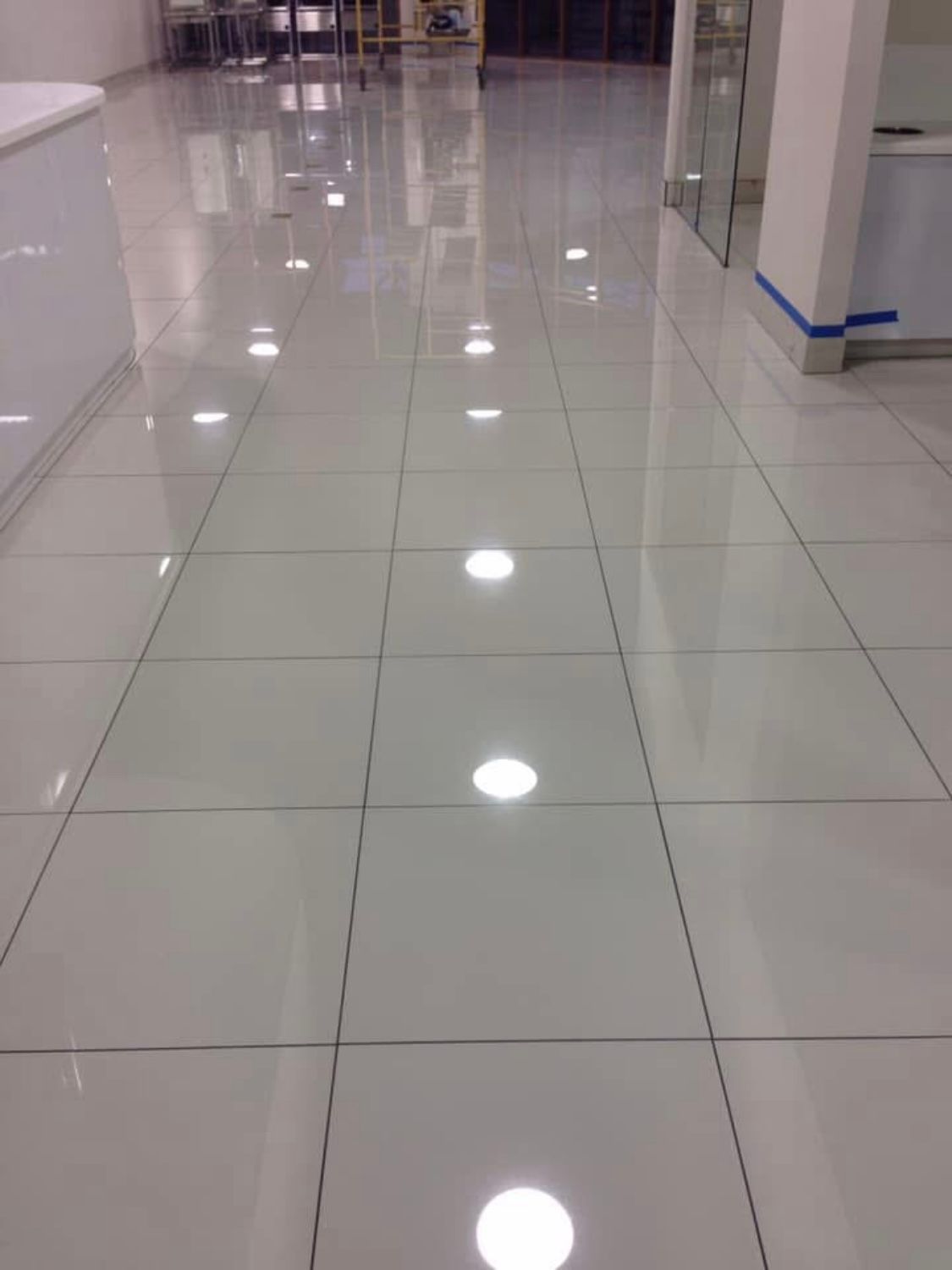 A white tiled floor in a room with a lot of lights on it.