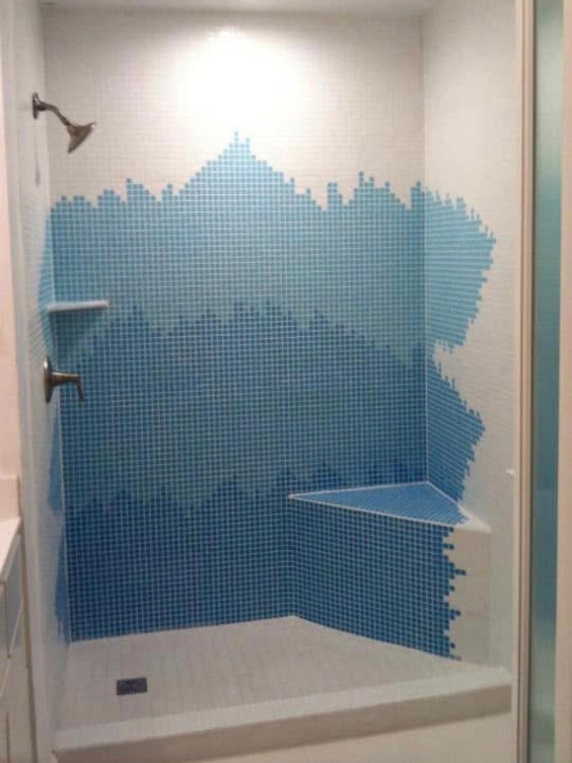 A shower with a blue tile wall and a shower head