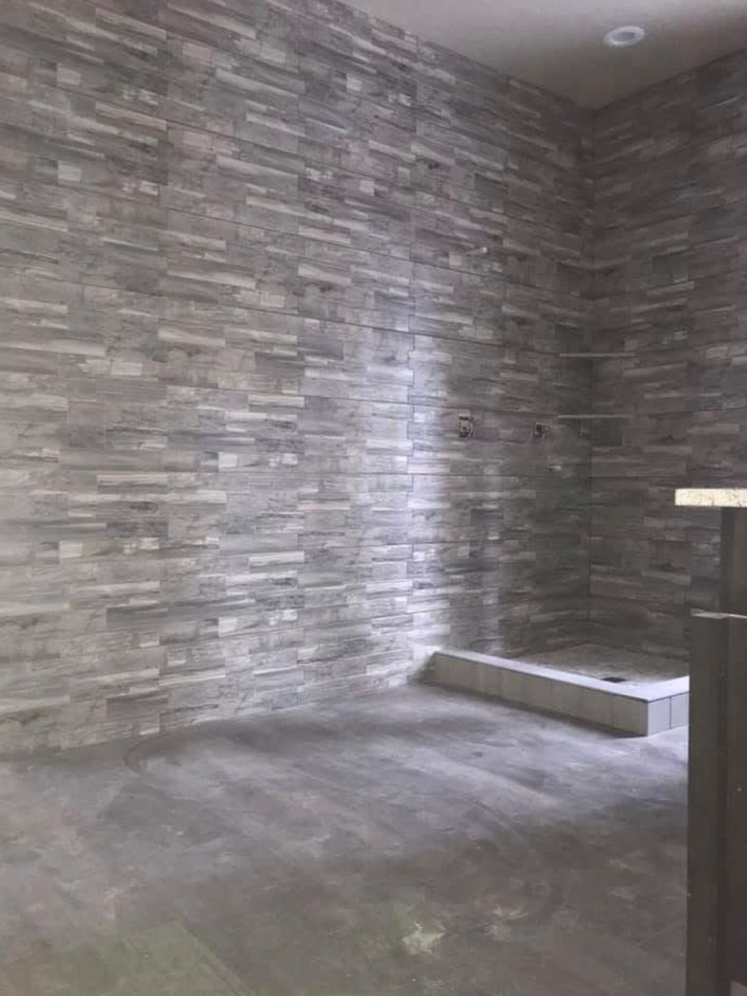 A bathroom with a walk in shower and a brick wall.