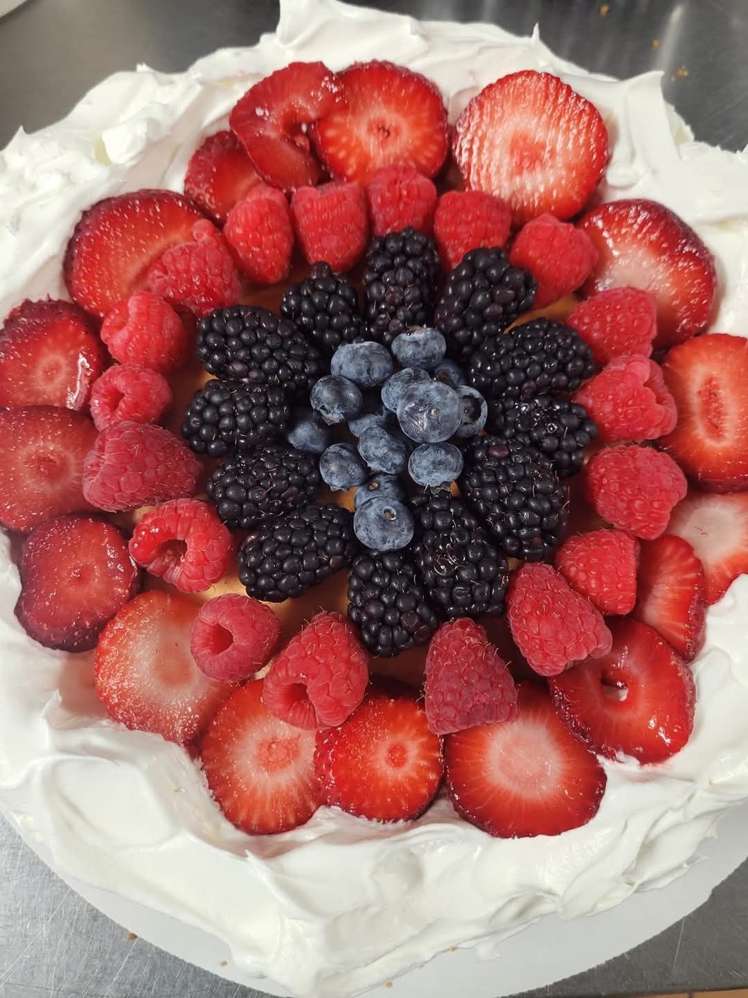 A cheese cake with strawberries raspberries blackberries blueberries and whipped cream