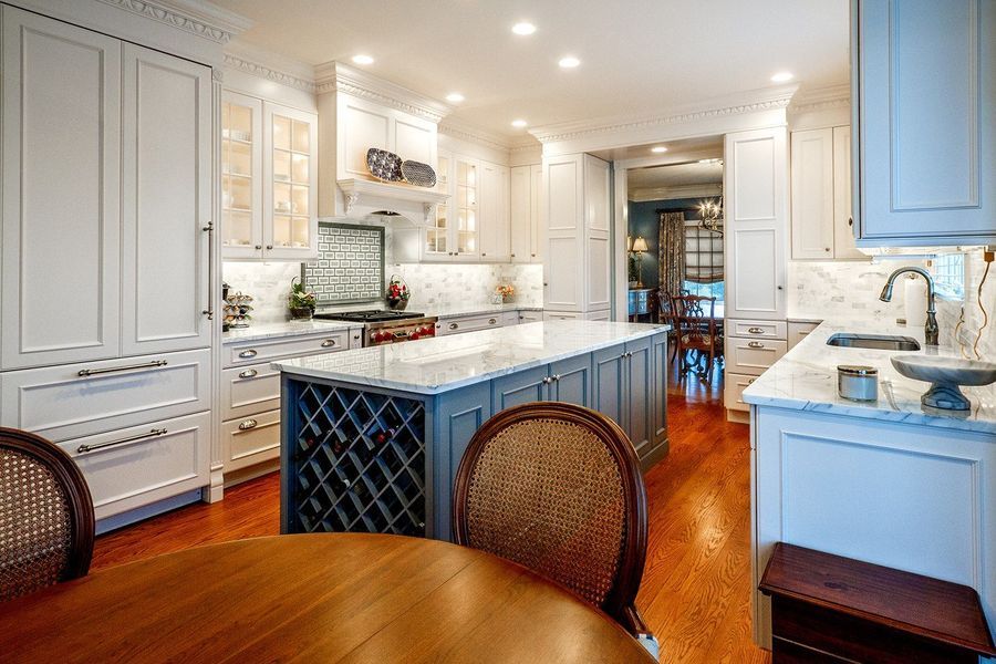 Spacious, bright kitchen with large island and white and grey cabinets. Wine rack built into island.