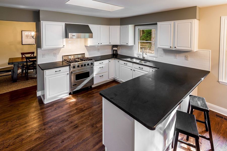 White kitchen with dark countertops, stainless steel appliances, and breakfast bar.