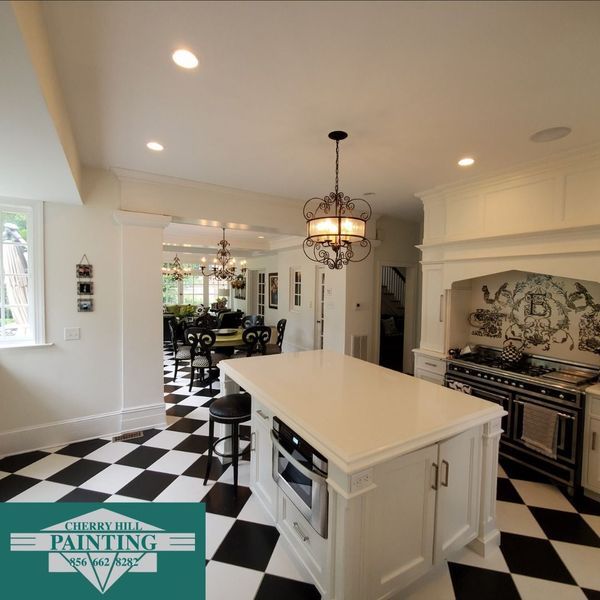 Kitchen with black and white checkered floor, white cabinets, island with microwave, and a dining room view.
