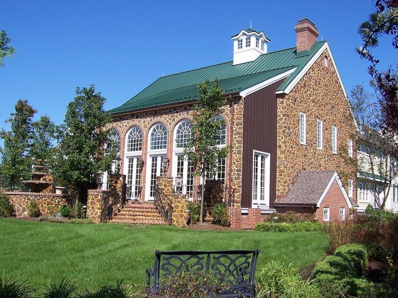 Stone building with arched windows, green roof, and lawn.