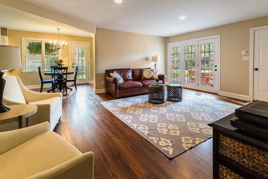 Living room with leather sofa, rug, french doors to patio, and dining area.