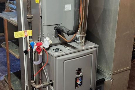 A furnace is sitting in a room next to a refrigerator.