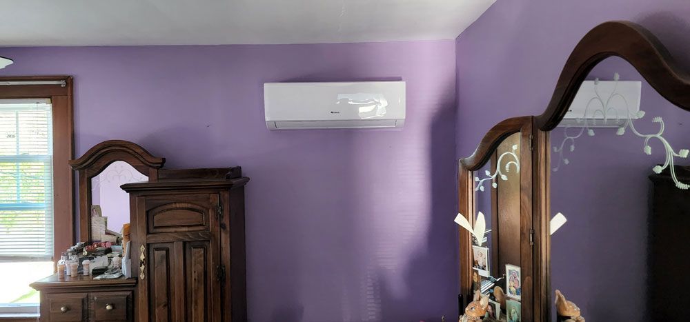 A bedroom with purple walls , a dresser and a mirror.