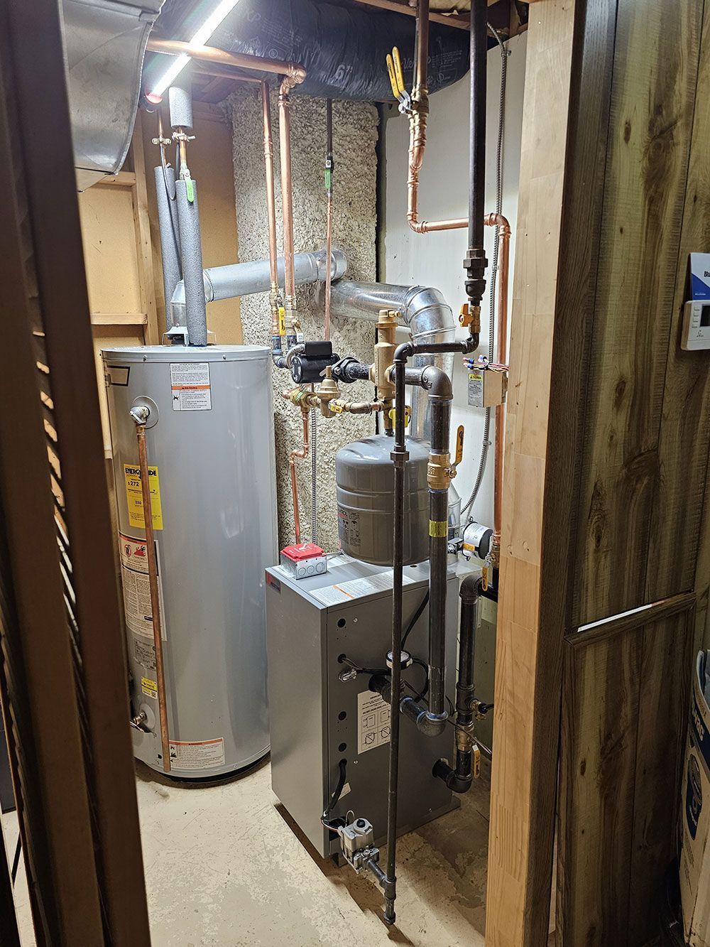 A room with a water heater and a furnace in it.
