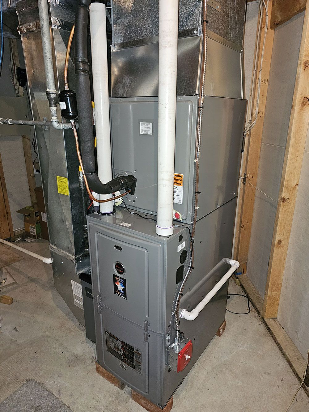 A furnace is sitting in a basement next to a wall.