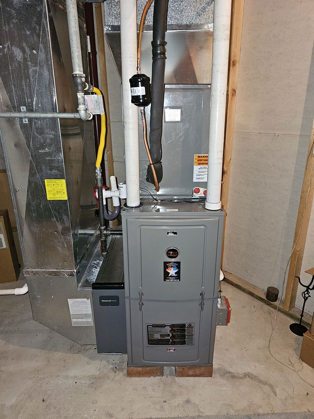 A furnace is sitting in a basement next to a wall.