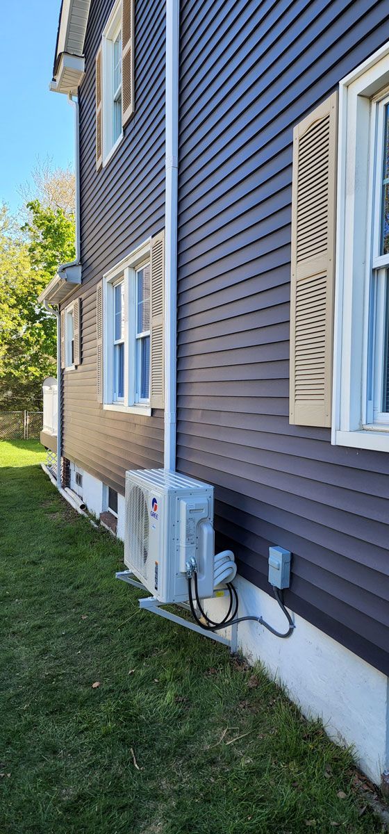 The side of a house with a purple siding and white windows.