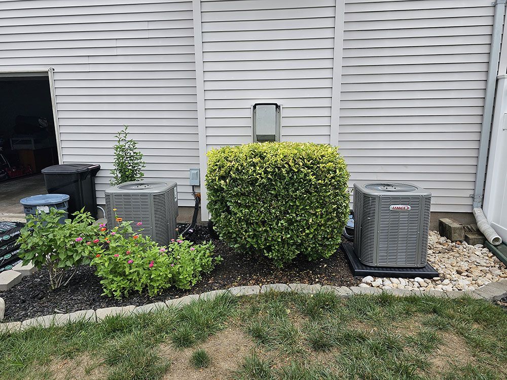 There are two air conditioners in the backyard of a house.