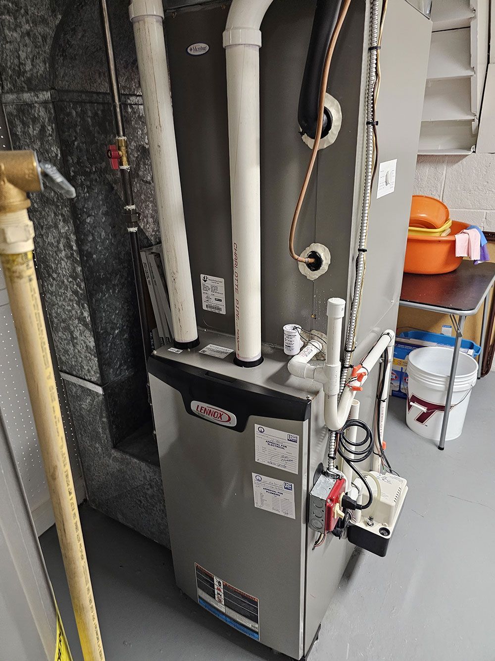 A furnace is sitting in a basement next to a staircase.