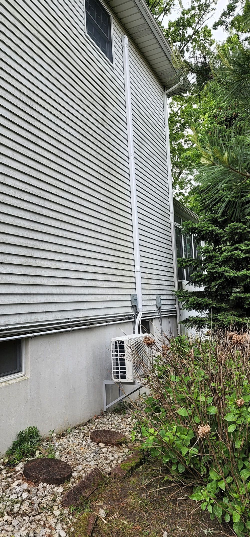 A white house with a drain pipe coming out of the side of it.