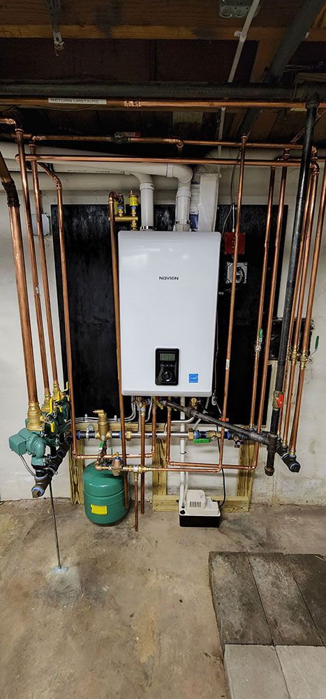 A boiler is hanging on a wall in a basement.