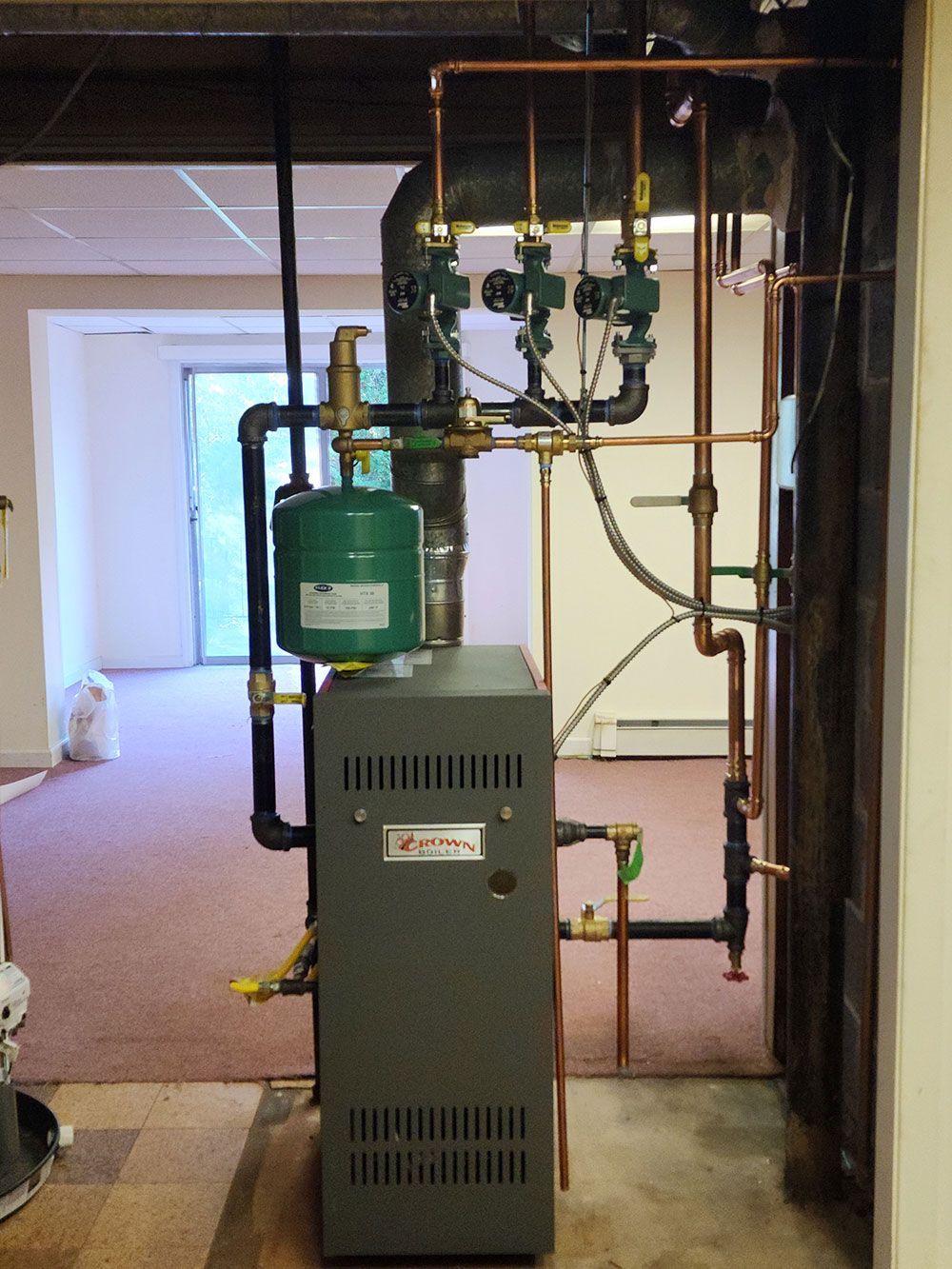 A boiler with copper pipes attached to it is in a room.