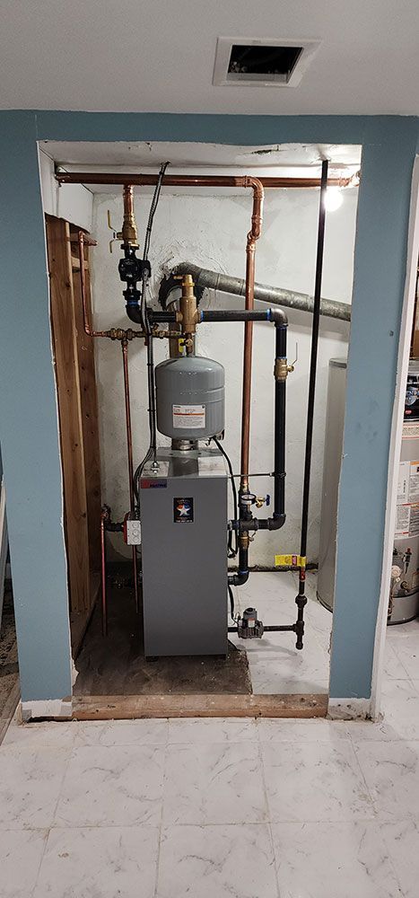 A room with a boiler and pipes in it.