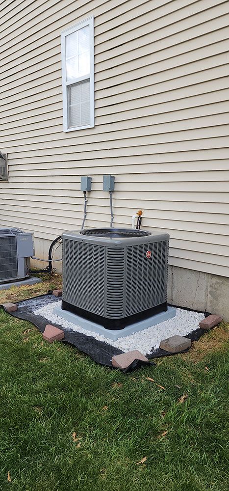 An air conditioner is sitting in the backyard of a house.
