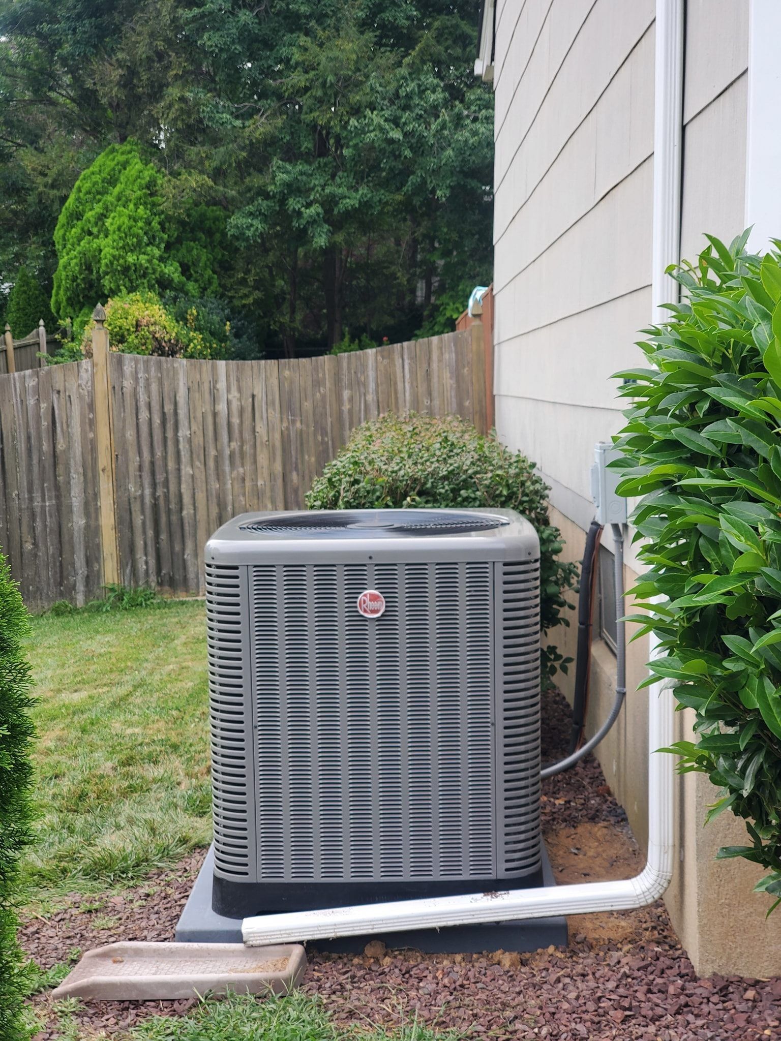 A large air conditioner is sitting on the side of a house.