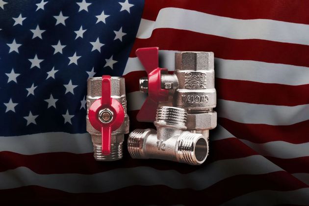 Red valve fittings in front of a waving American flag background