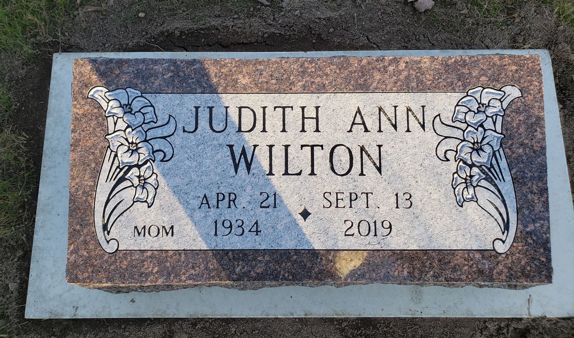 Grave marker of Judith Ann Wilton, born April 21, 1934, died Sept 13, 2019. Floral designs frame her name.