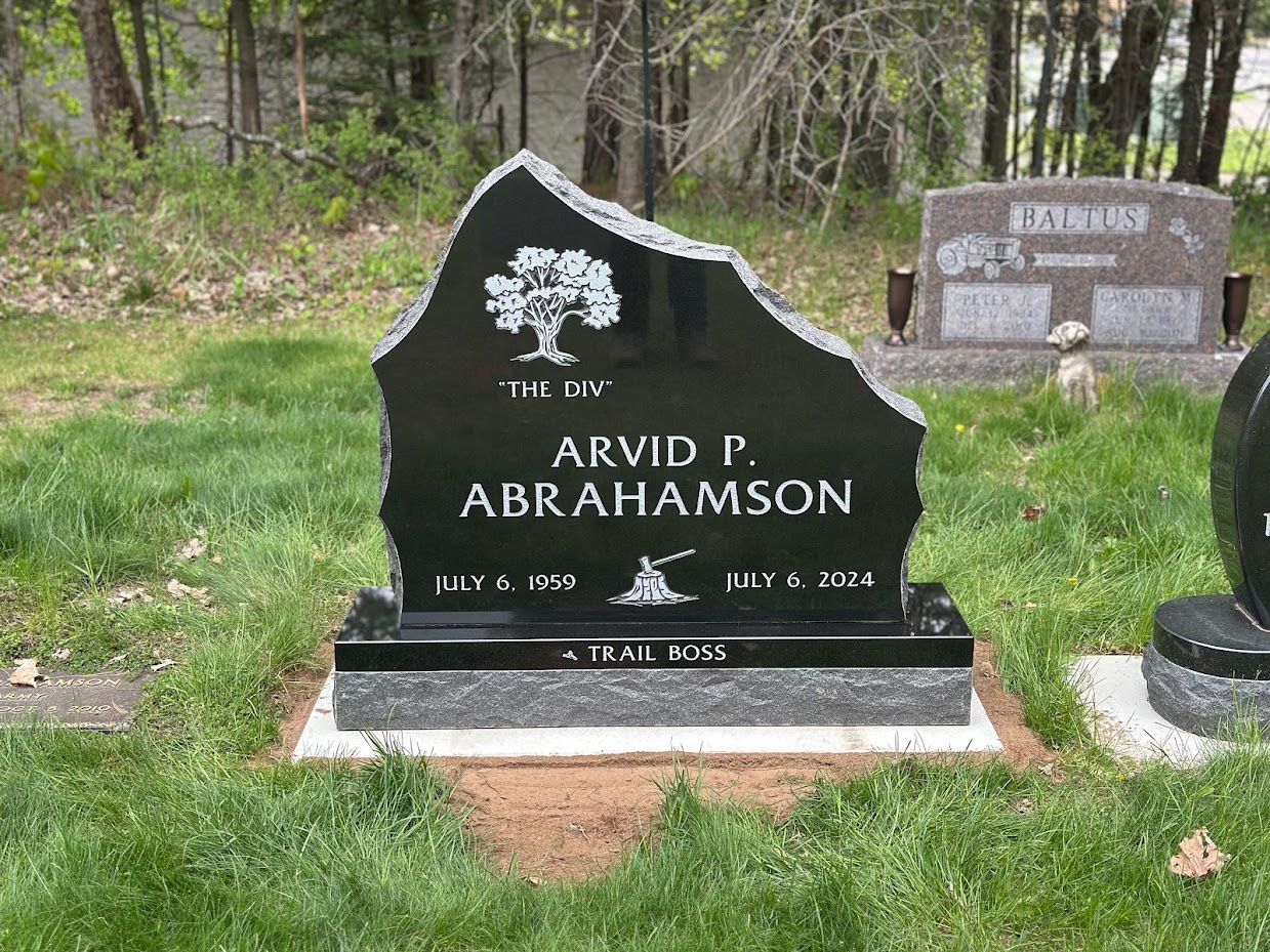 Black tombstone with tree carving, text 