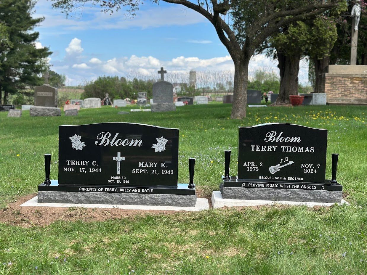 Two black headstones in a cemetery, 