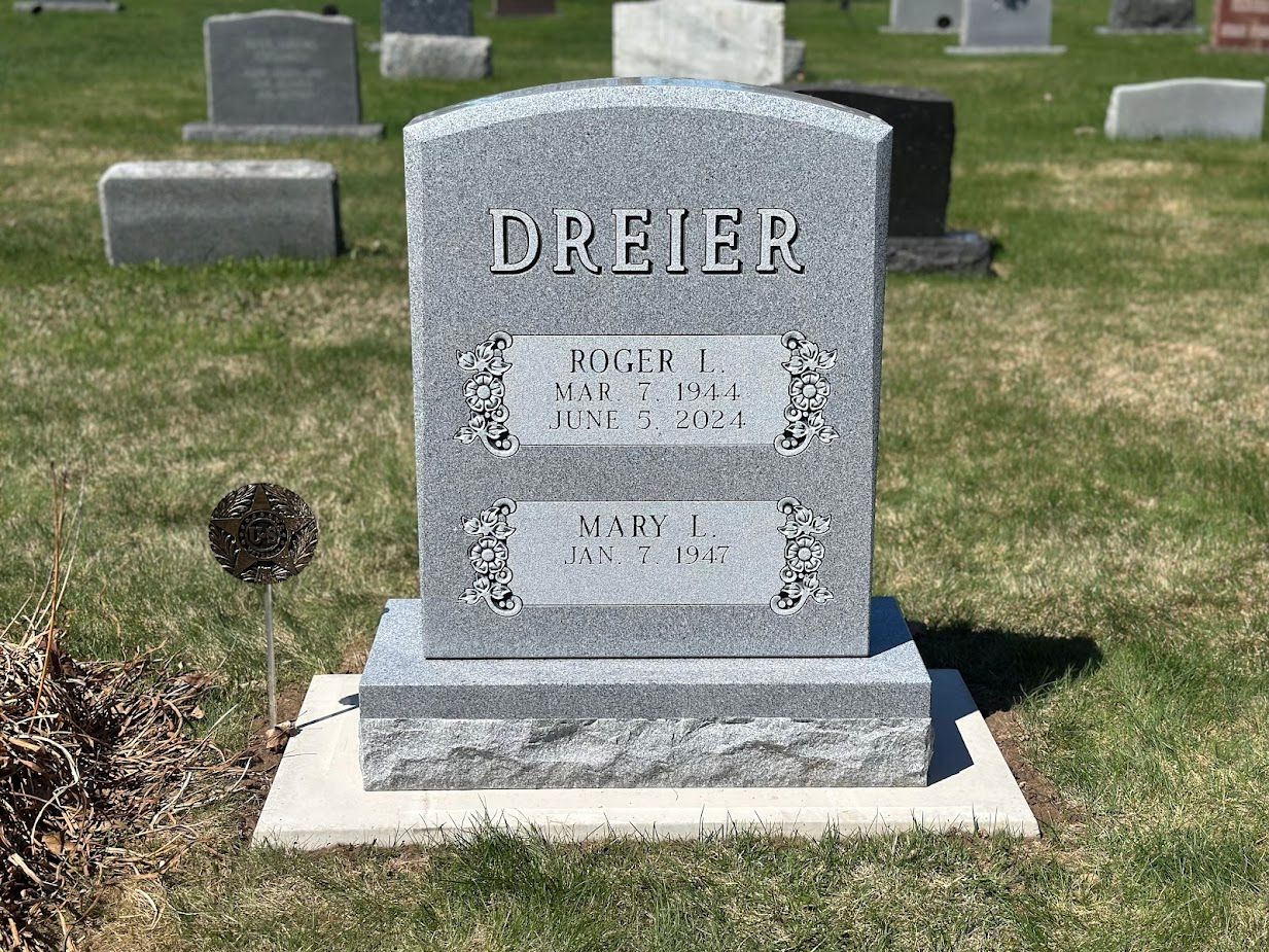 Gray headstone in a cemetery, inscribed with 