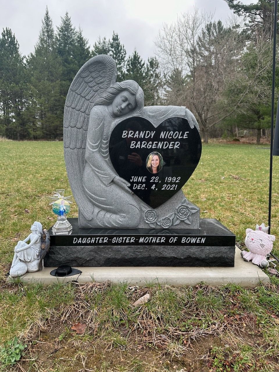 Gravestone of Brandy Nicole Earsender with angel, heart, photo, and floral decorations.