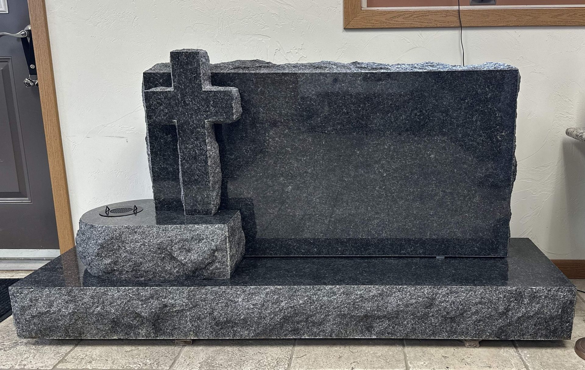 Dark granite tombstone with a cross, on a base.