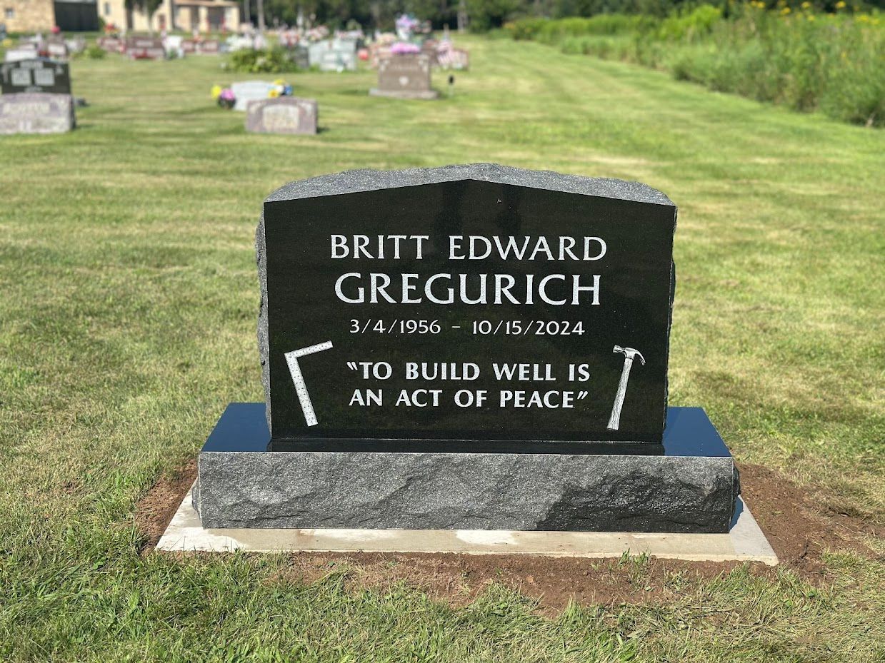 Black granite headstone in a cemetery.  Inscribed: Britt Edward Gregurich, dates, 