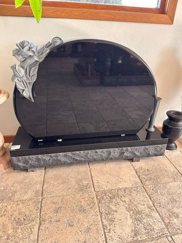 Black granite headstone with a rounded top, gray rose, and a dark gray base.