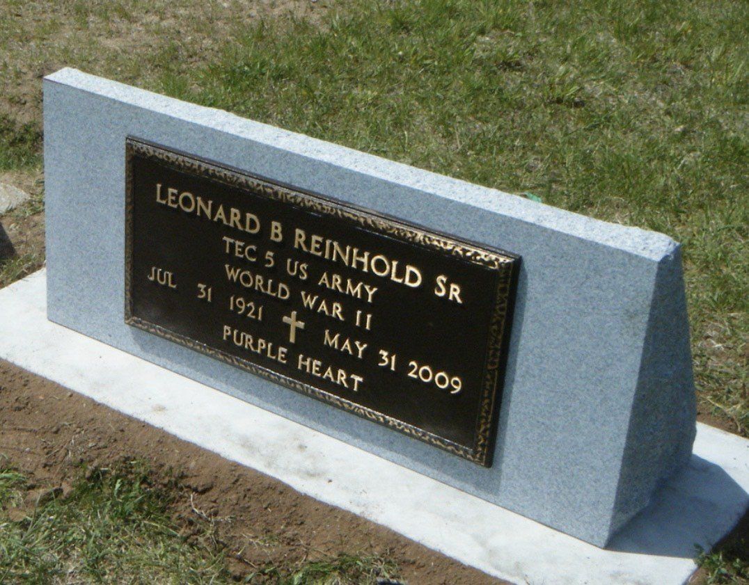 Gravestone of Leonard B. Reinhold Sr., a WWII Purple Heart recipient. Brown plaque on a granite slab.