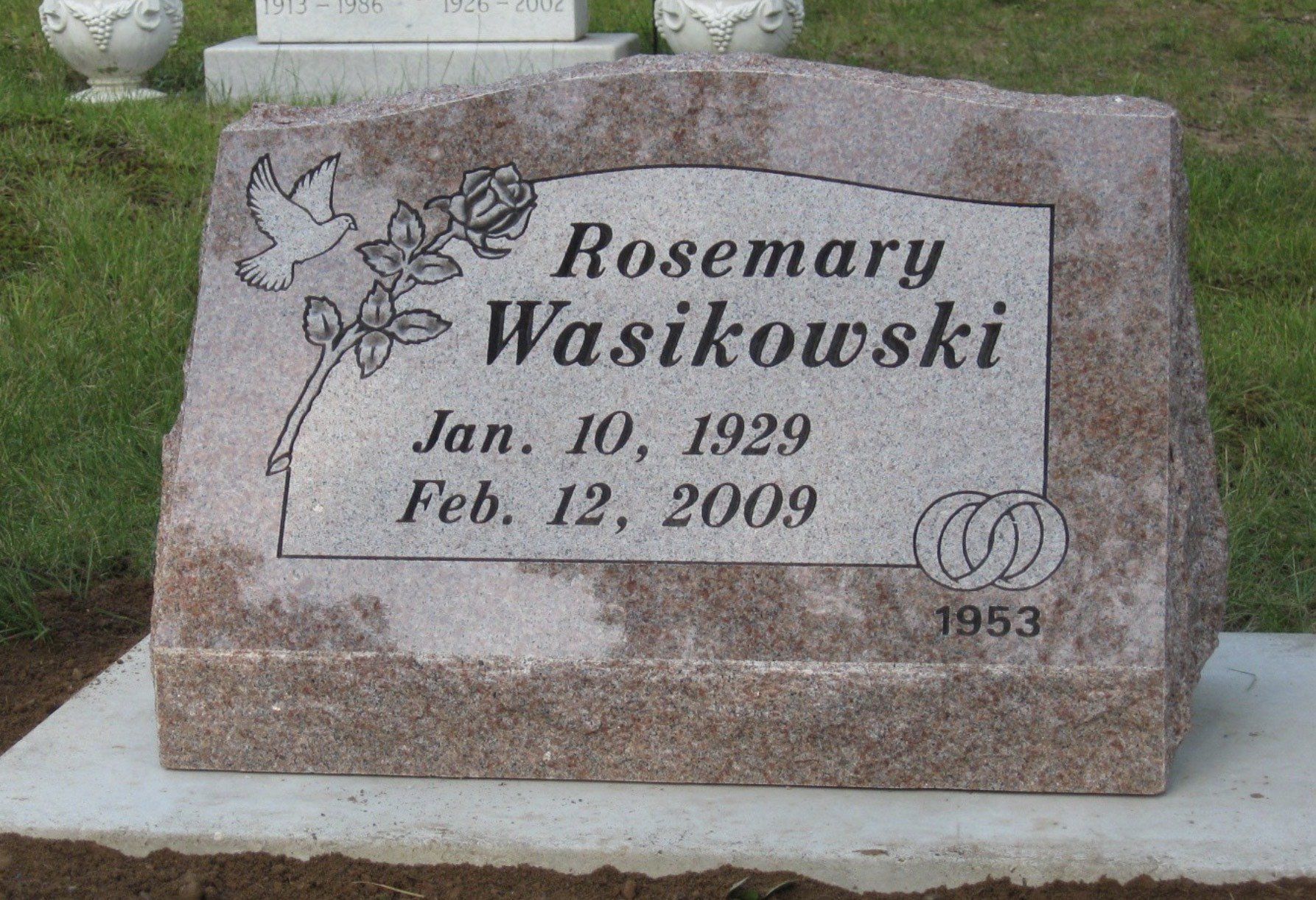 Headstone for Rosemary Wasikowski (1929-2009). Pink granite with dove, rose, and wedding rings.