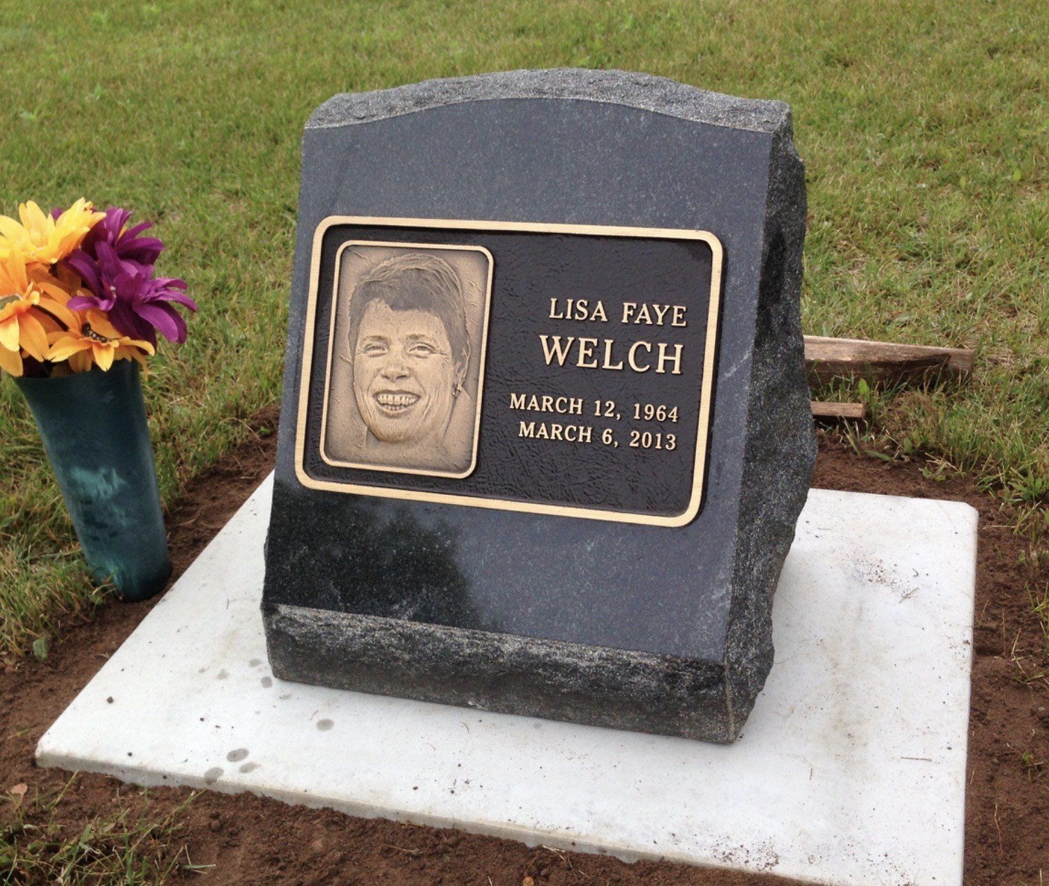 Headstone of Lisa Faye Welch with bronze portrait and inscription, flowers.
