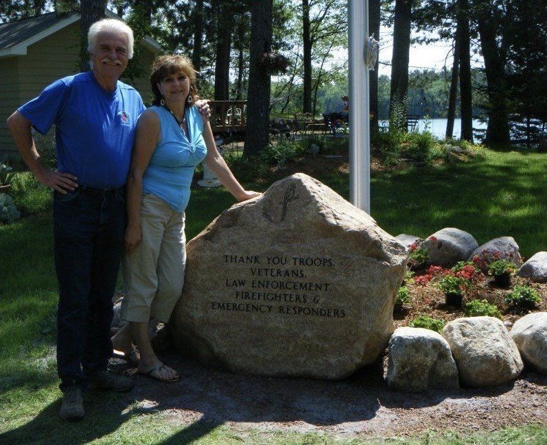 A man and woman stand by a rock monument thanking veterans, law enforcement, and first responders.