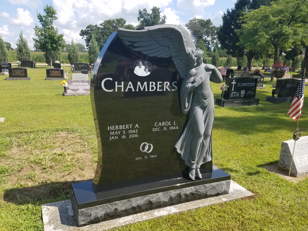 Black granite headstone in a cemetery; features the names 