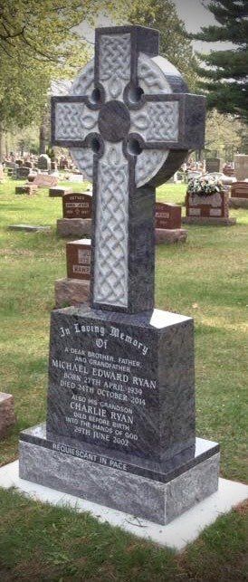 Celtic cross headstone in a cemetery. Black stone with engraved inscription.