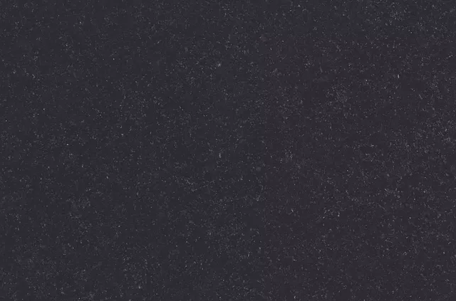 Dark gray, textured surface with subtle speckles.