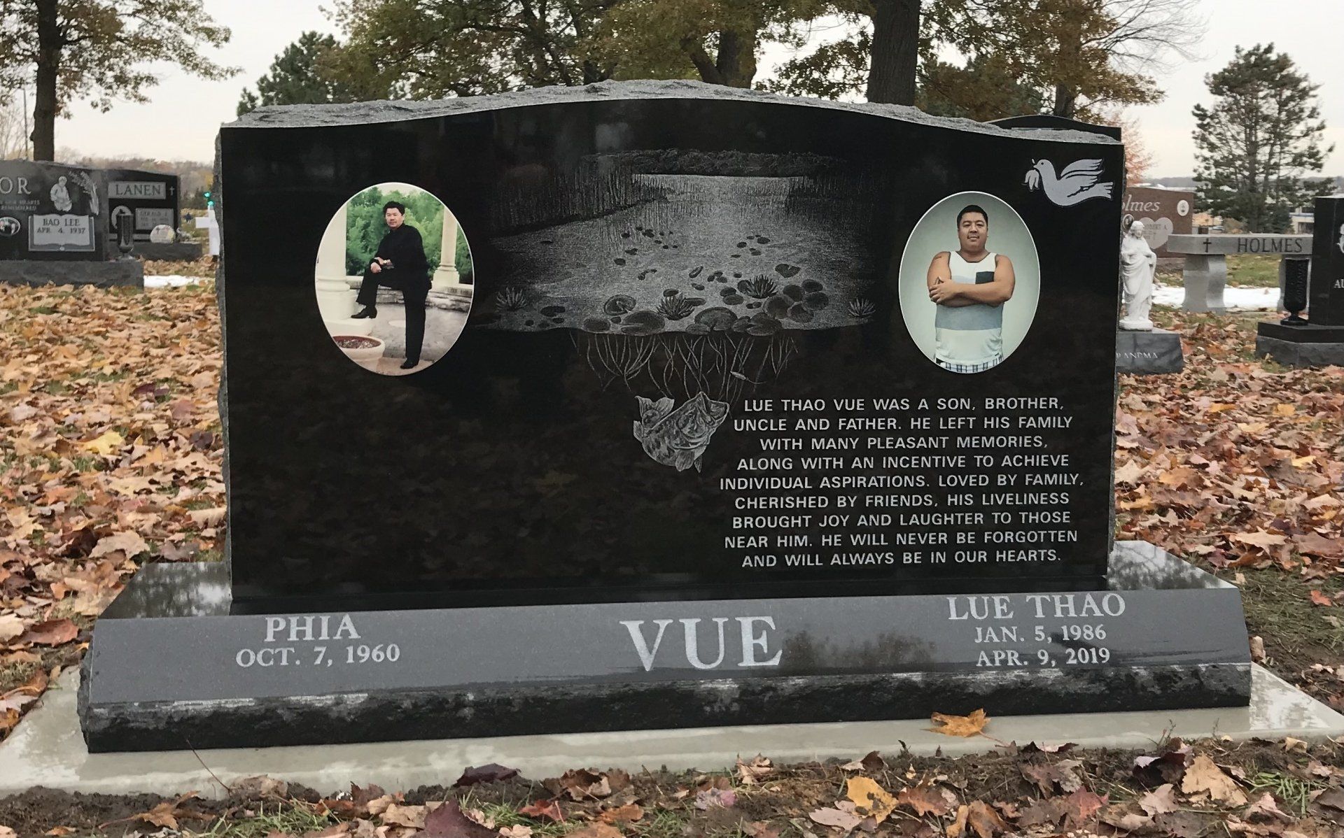 Black granite tombstone with two framed photos of men; a man standing and a man with crossed arms; VUE is the last name.