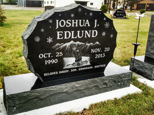 Black granite headstone with name, dates, and illustration of a person.