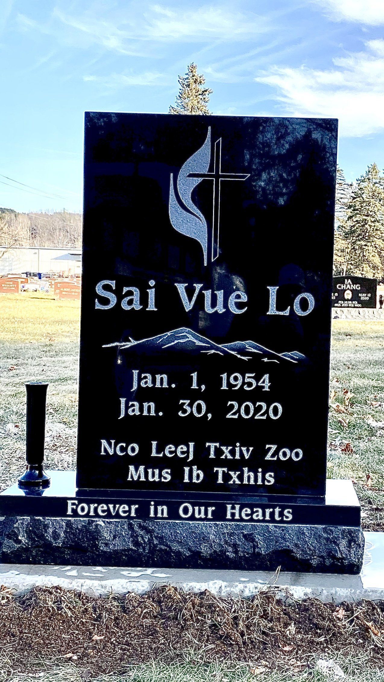 Black headstone for Sai Vue Lo with dates 1954-2020, Hmong text, and a stylized cross.
