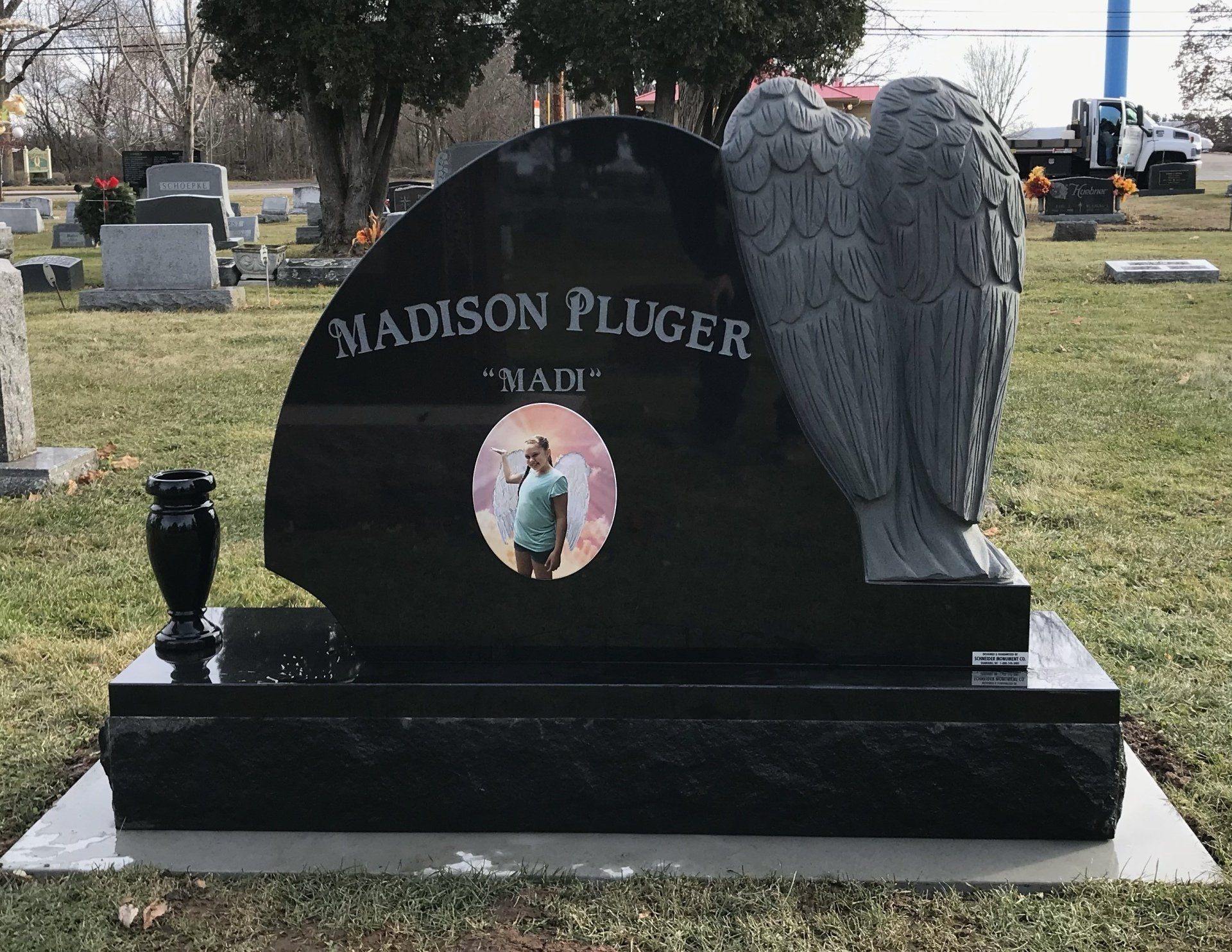 Black granite headstone with angel wings, a photo of a person, and the name 