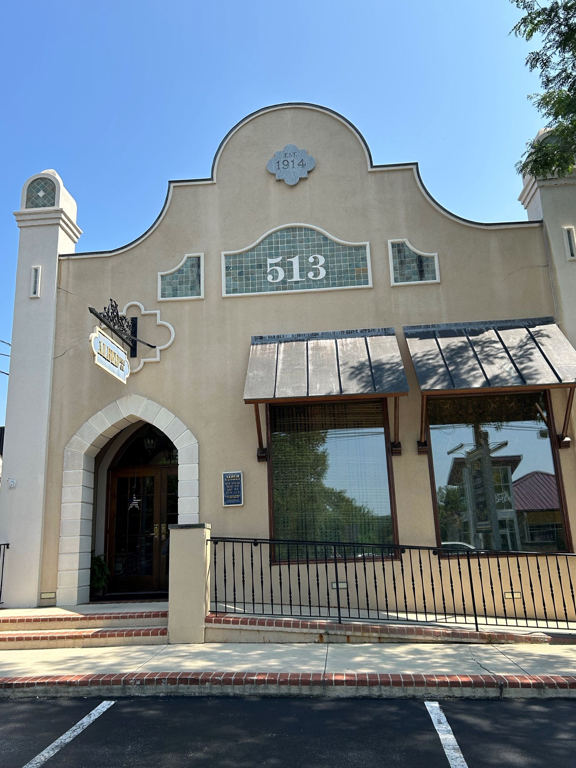 Tan stucco building with arched entrance, windows, and the number 