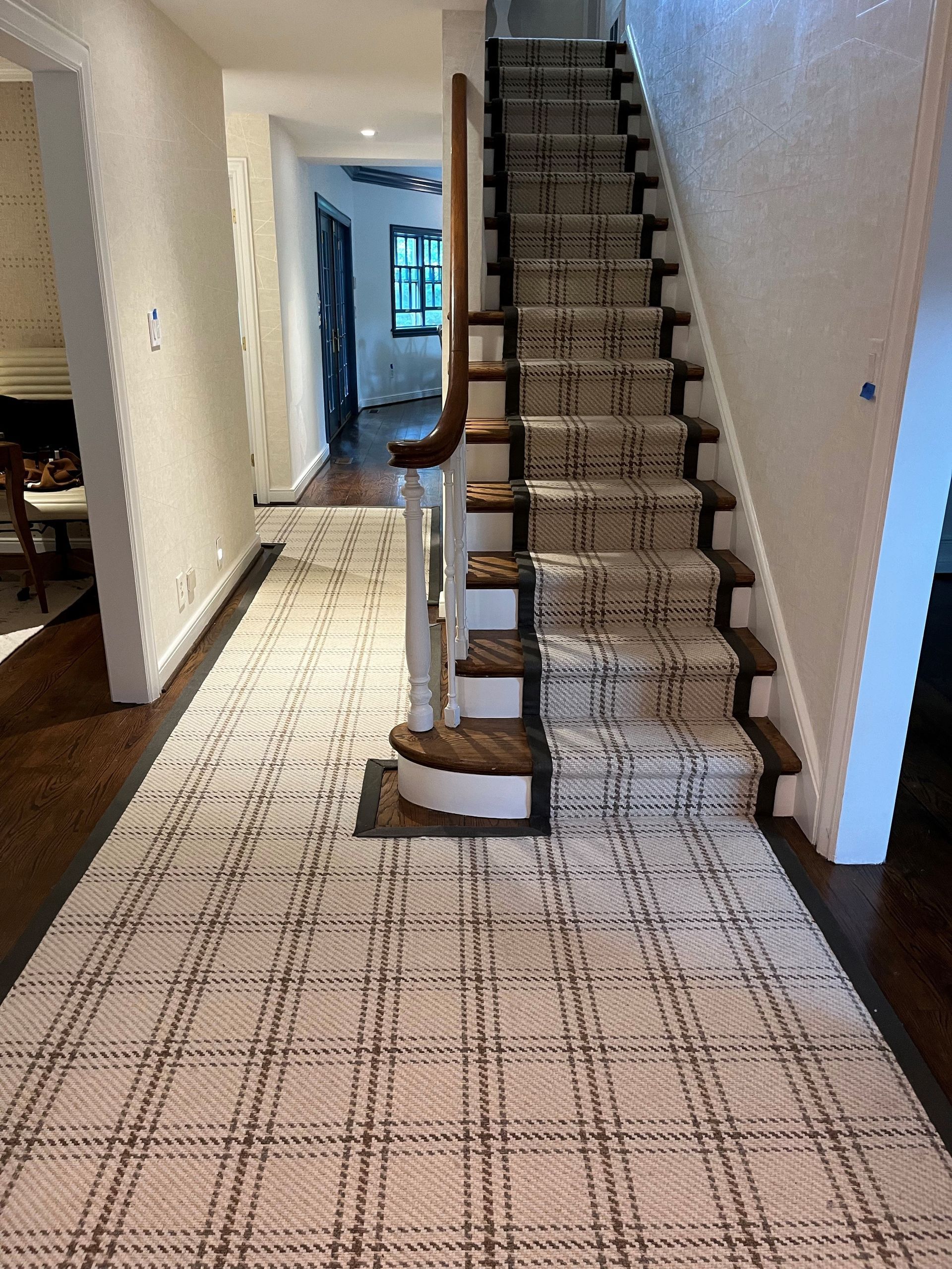Hallway with patterned carpet and stairs. The carpet has a plaid design, and the stairs have matching runners.