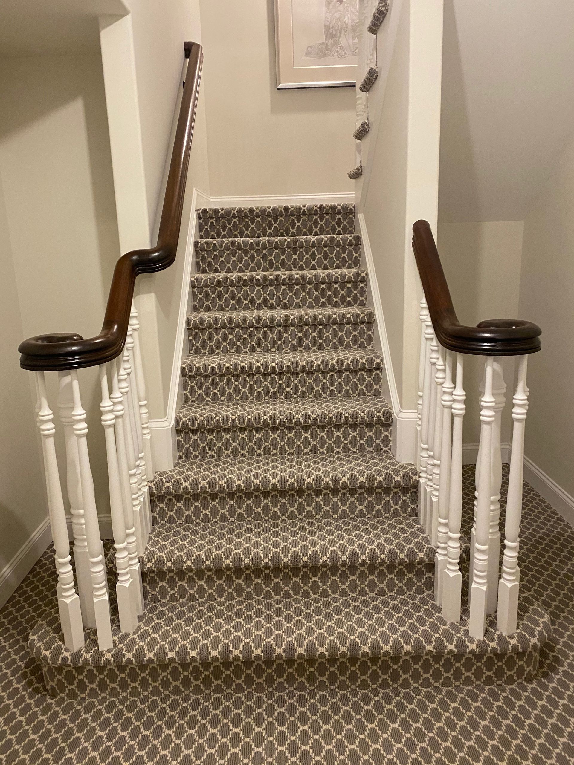 Staircase with patterned carpet and white balusters; dark wood handrails and newel posts. The stairs lead upwards.