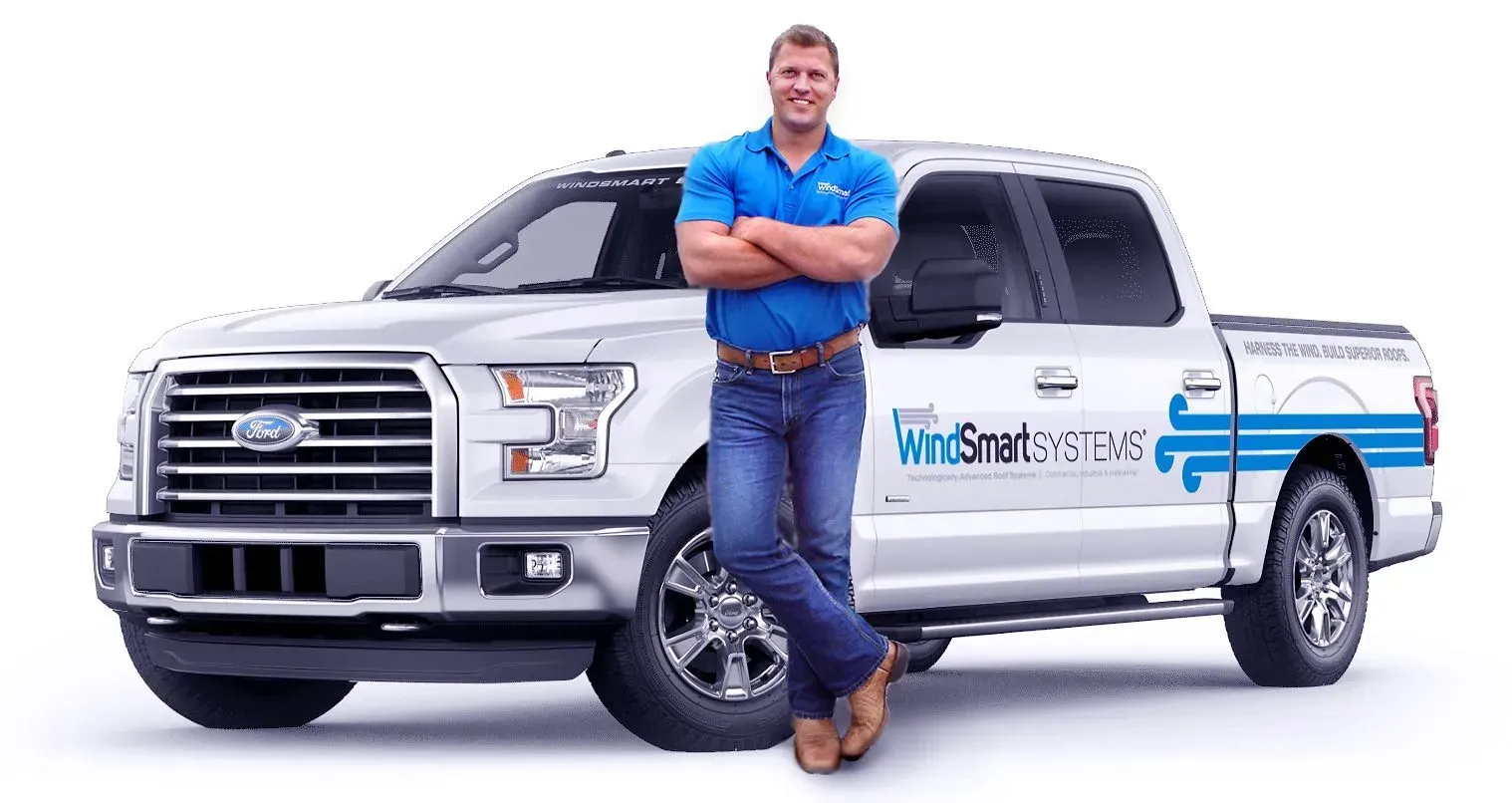 Man in blue shirt and jeans with arms crossed, leaning against a white truck.